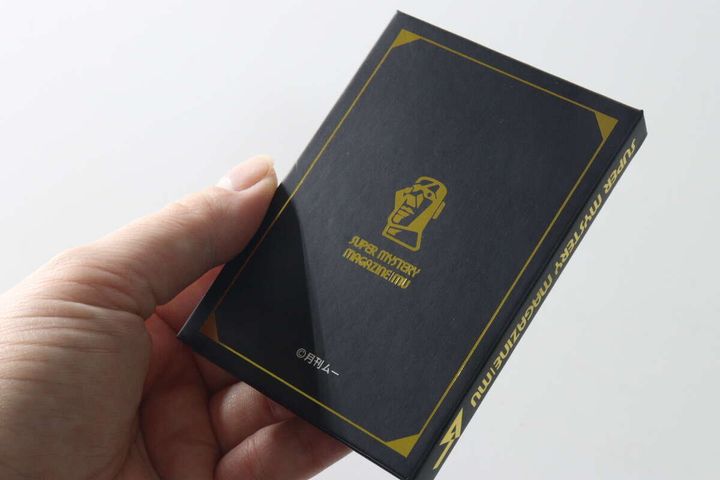 手に持ったブック型メモ帳の裏表紙。モアイ像の箔押しデザイン