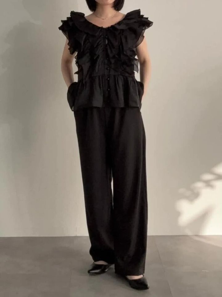 フリル黒ブラウスとワイドパンツでオールブラックコーデの女性