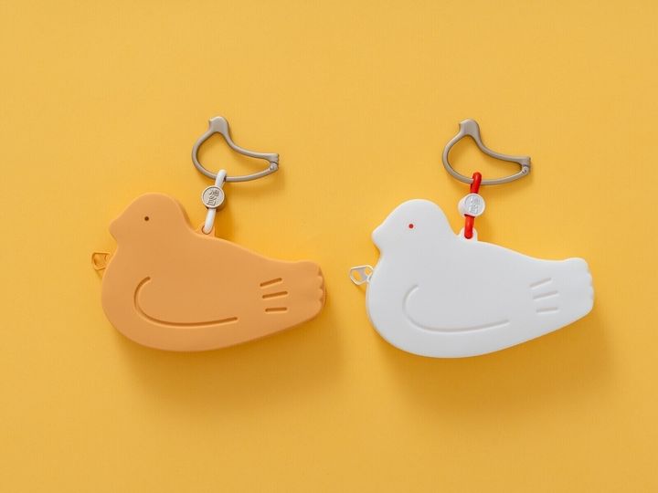 株式会社豊島屋は、2026年8月10日の「鳩の日」に、限定商品としてシリコンポーチ「はとっこ」を販売します。鳩サブレー1枚がぴったり収まるサイズで、カラーは「茶」と「白」の2種類用意しています。※画像：株式会社豊島屋