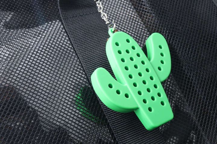 緑色のサボテン型キーホルダーが黒いメッシュ素材のバッグに付けられている