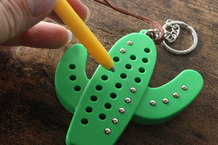 指で持った黄色いペンを、サボテン型キーホルダーの穴に差し込んでいる様子