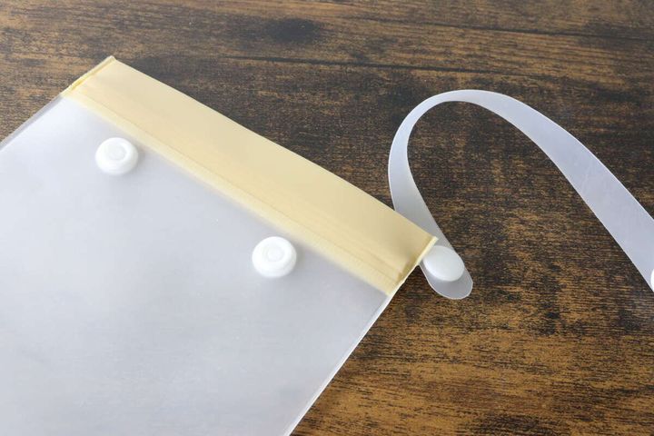 チャック袋のストラップをスナップボタンで外している