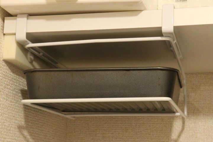 吊り戸棚ラックに深さのあるオーブン皿を収納している様子
