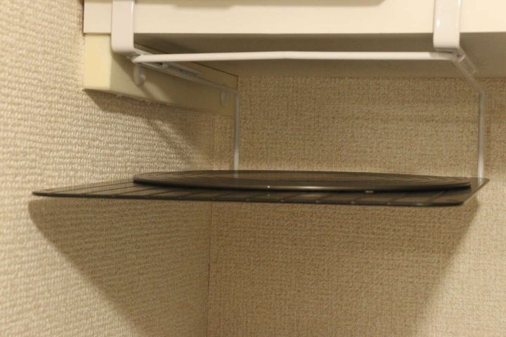 吊り戸棚ラックに黒い丸いまな板を収納している様子