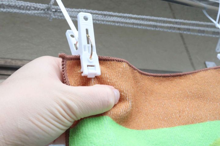 手が干されたタオルを下に引っ張りピンチを外している瞬間