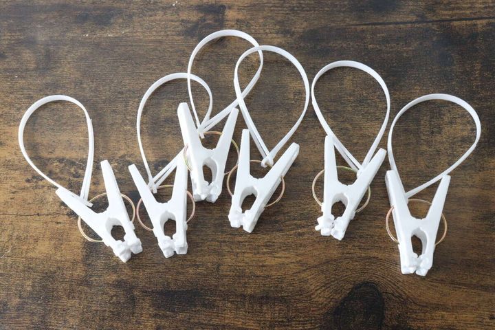 白いひも付き洗濯ピンチ6個が木目調の台に並べられている