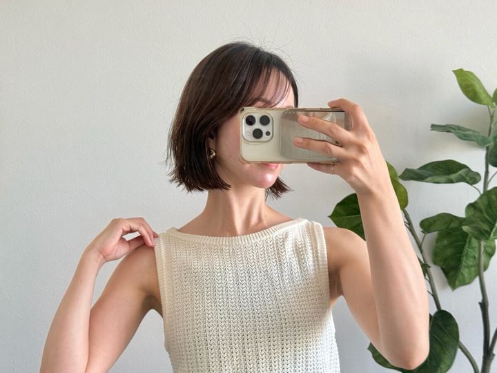 白いニットタンクトップを着た女性が肩を見せている