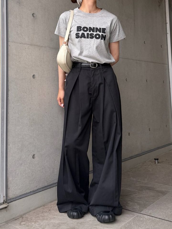 グレーのロゴTと黒のワイドパンツを着用し、ウエストマークした女性