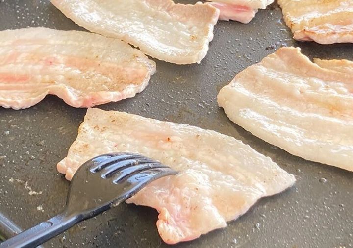 ホットプレートで焼かれている豚バラ肉を、黒いPPS樹脂製フォークでひっくり返している