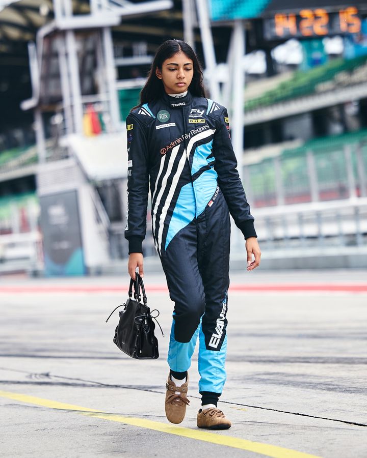 レーシングスーツ姿でCHARLES & KEITHのバッグを持つKareen Kaur