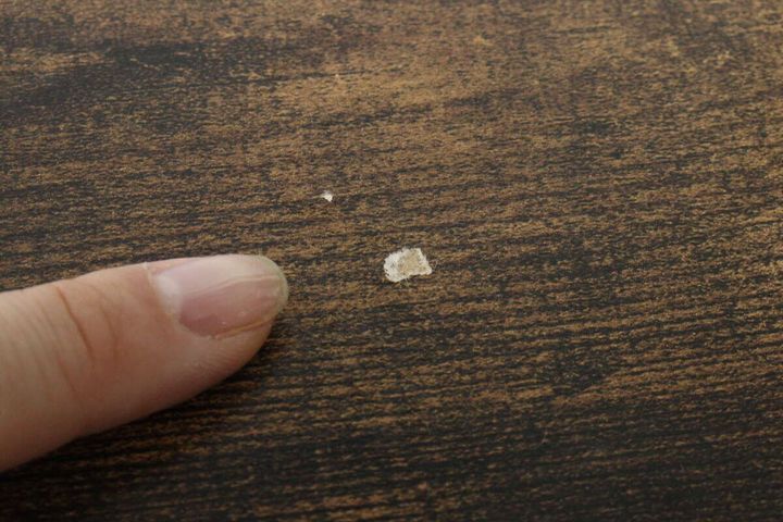 木目調のテーブルにできた小さな白いキズを指で指し示している