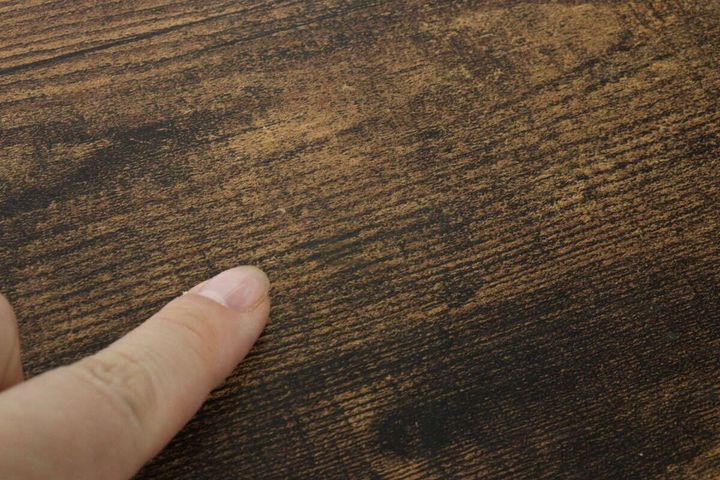 木目調のテーブルの補修箇所を指で指し示しており、キズが目立たなくなっている
