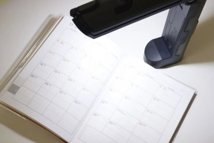 展開した作業ライトで開いた手帳を照らしている