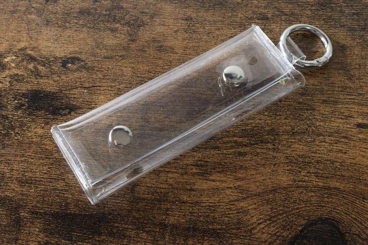 透明なPVCコインポーチが木目のテーブルに斜めに置かれている