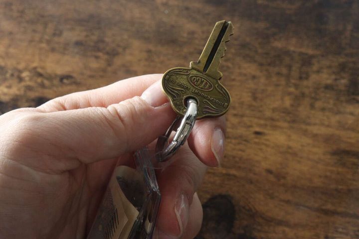 手がPVCコインポーチから伸びるリングに付いた鍵を持っている