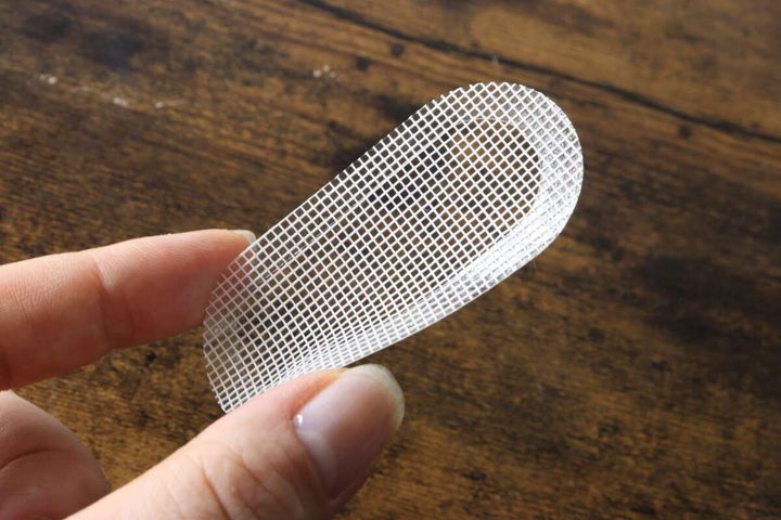 指でつまんで持ち上げられた白いメッシュ素材の防虫シール