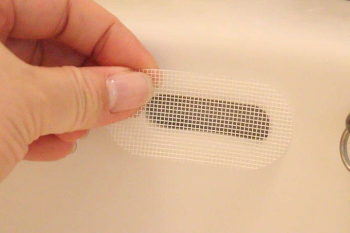 洗面台のオーバーフロー穴に防虫シールを貼り付ける様子