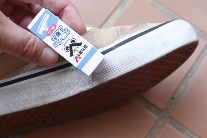 ベージュのスニーカーの白いソール部分を消しゴムで擦って汚れを落としている