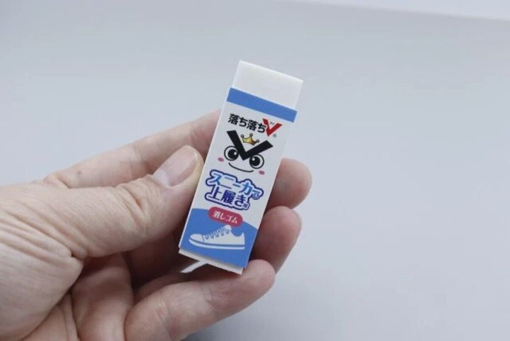 「落ち落ちV」と書かれたスニーカー＆上履き用消しゴムを女性が指でつまんで持っている