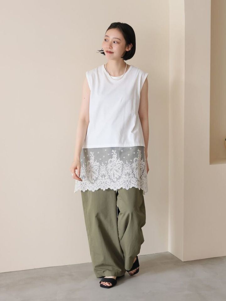 白のノースリーブチュニックとカーキのワイドパンツを着用した女性