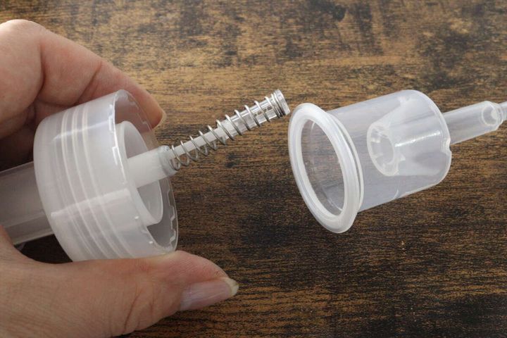 泡ポンプボトルのポンプ部分が分解され、バネや部品が見えている