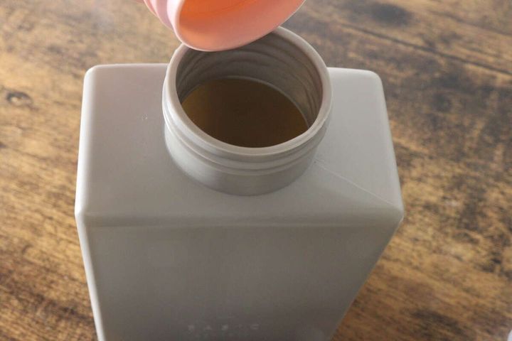 グレーの泡ポンプボトルの広い注ぎ口に、ピンクのじょうごが差し込まれている