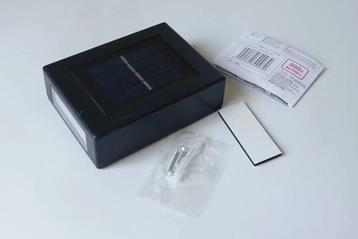 黒いソーラーライト本体と取り付け用のネジ、粘着テープ