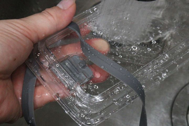 密閉容器のフタとパッキンを流水で洗っている手元