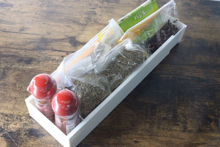 白い伸縮ケースに袋入りのスパイスや調味料ボトルを収納している様子