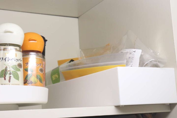白い吊り戸棚の中に調味料を収納した伸縮ケースが収まっている様子