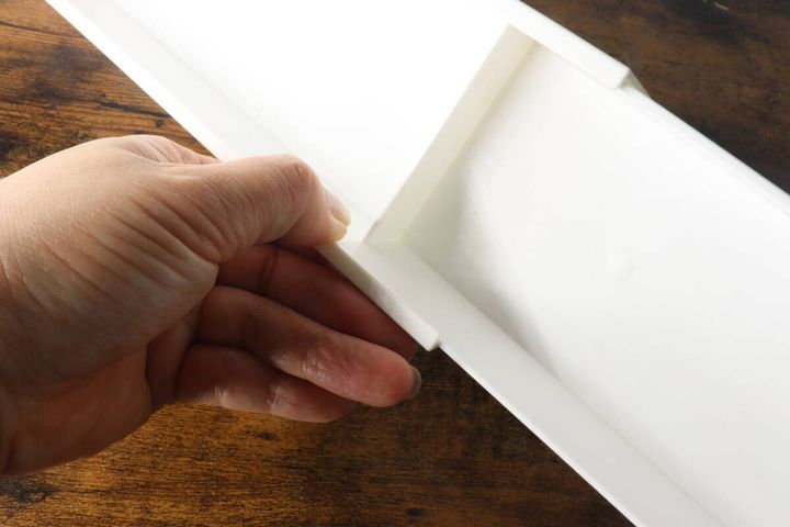 白い伸縮ケースのストッパー部分を指で押さえている手元