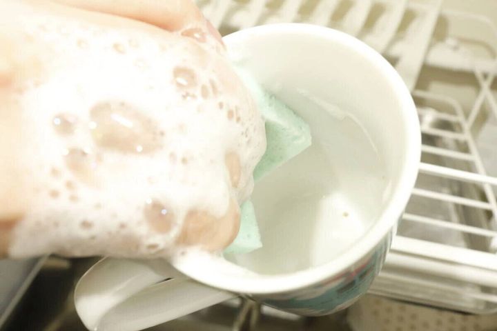 泡立てたシートスポンジでマグカップを洗う手元