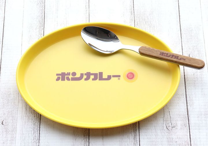 黄色いボンカレー皿にスプーンが置かれているアップ。木目調の柄にボンカレーロゴ