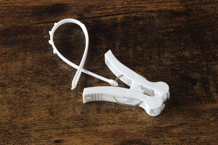 白い洗濯ピンチ1個と、物干し竿固定用の白い紐