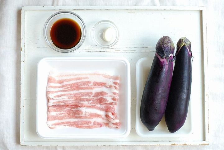 白い木製の板の上に並べられた、なす、豚バラ肉、ポン酢、にんにく