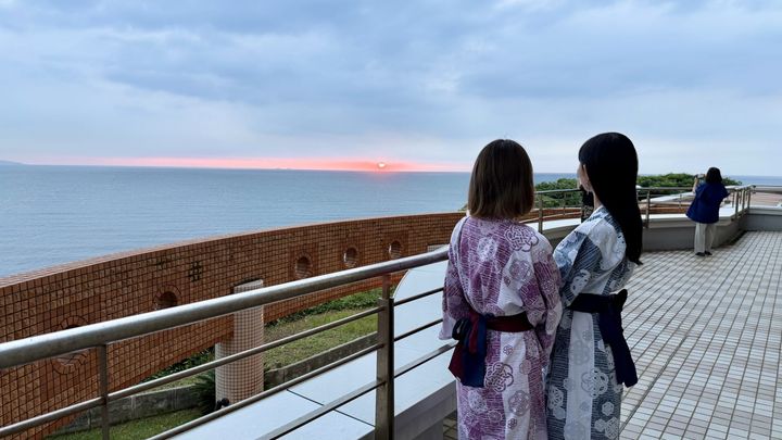 浴衣を着た二人の女性がテラスから夕焼けを眺める様子