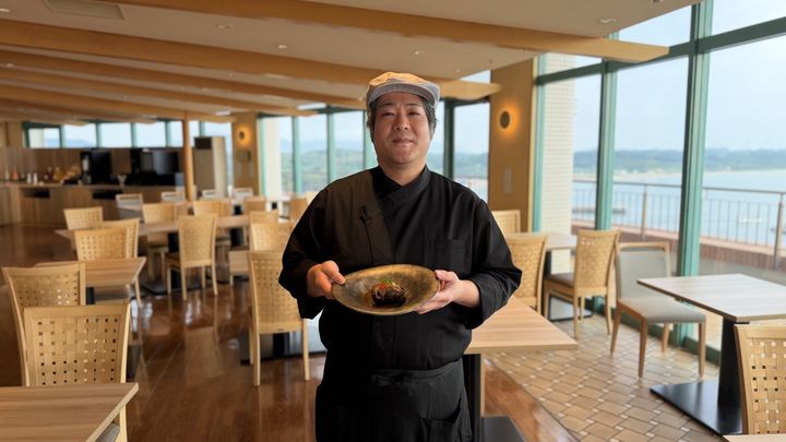 料理を持って微笑む料理長・工藤徹法氏