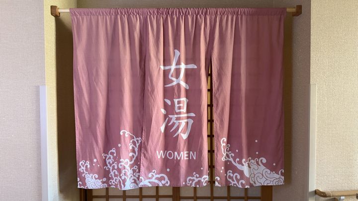 温泉入口にかかる女湯のピンク色の暖簾