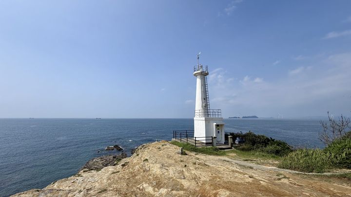 青い海と空を背景に岬に立つ真っ白な妙見埼灯台