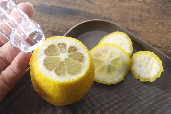 カットしたレモンにレモンジューサーを差し込もうとしている