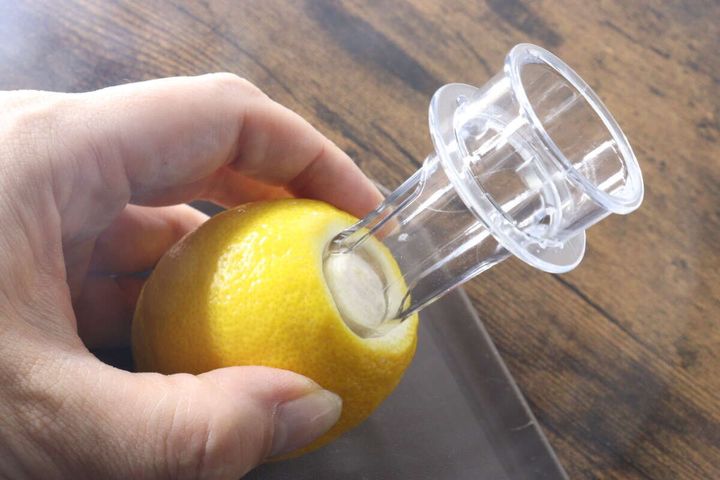 レモンジューサーをレモンの白い部分に差し込んでいる