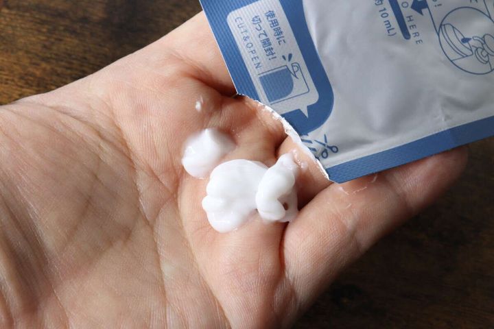 カットしたfrospa詰め替えパウチから白い日焼け止めを出している手元