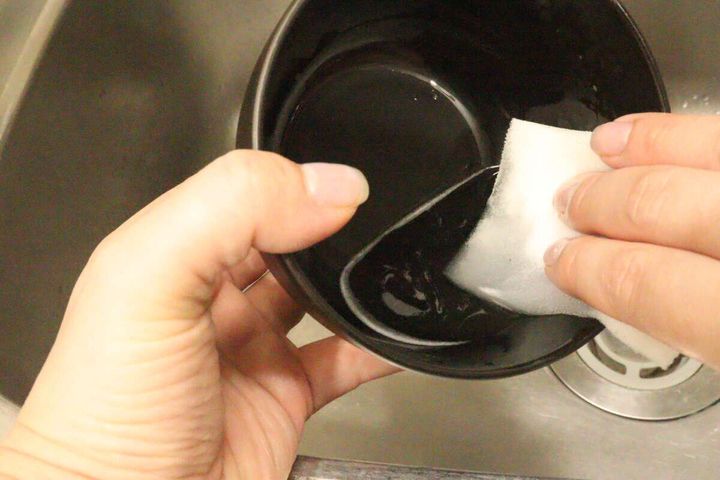 女性がシンクで汁椀をスポンジで洗っている