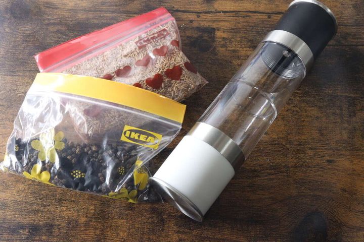 木目のテーブルに置かれた2WAYグラインダーとスパイスの袋2つ