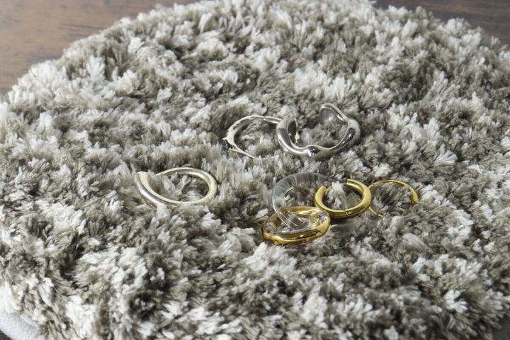 タフティングマットの上に置かれた複数の指輪やイヤーカフなどのアクセサリー
