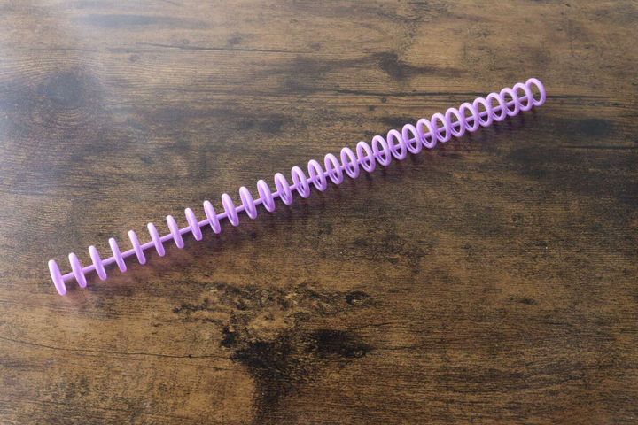 木目のテーブルに紫色のルーズリーフリングが一本置かれている
