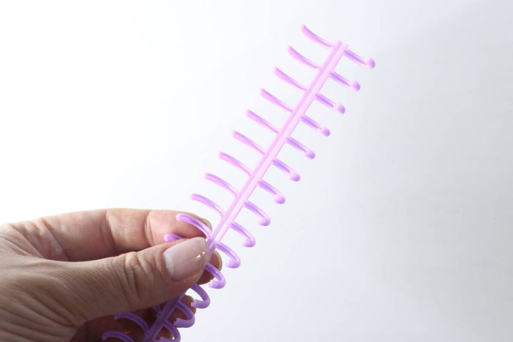 指でリングを開いている紫色のルーズリーフリング