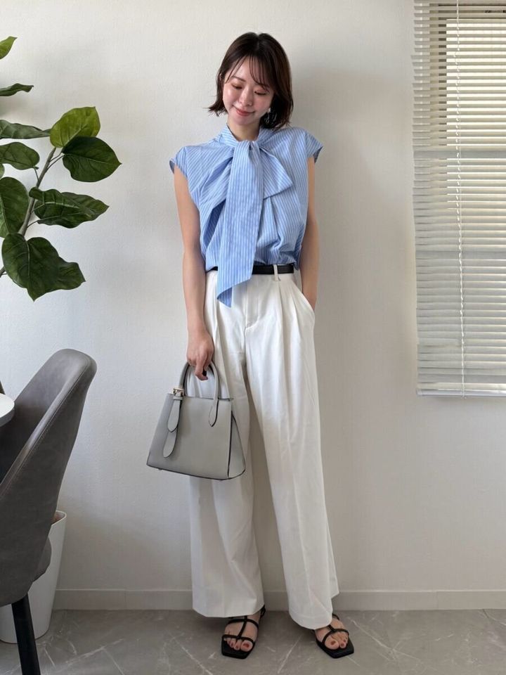 白いパンツに水色のボウタイブラウスを合わせた女性のオフィスコーデ