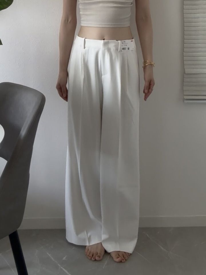 白いスマートワイドストレートパンツを着用した女性の全身、商品タグ付き
