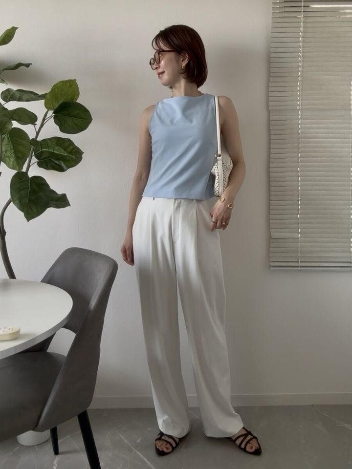 白いパンツに水色のノースリーブトップスを合わせた女性の夏コーデ、白いミニバッグ
